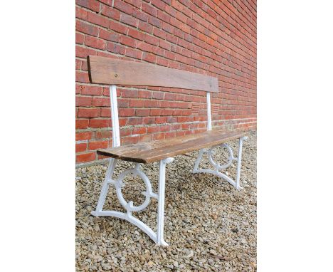 AN OLD WHITE PAINTED GARDEN BENCH with cast iron ends and varnished wooden back and seat, 148cm wide x 80cm high Condition: s