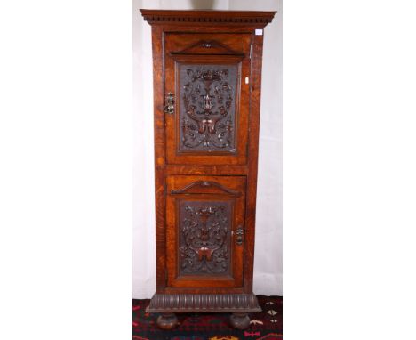 Late Victorian oak floor standing corner cabinet having dental work cornice above two shield cartouche and floral spray inset