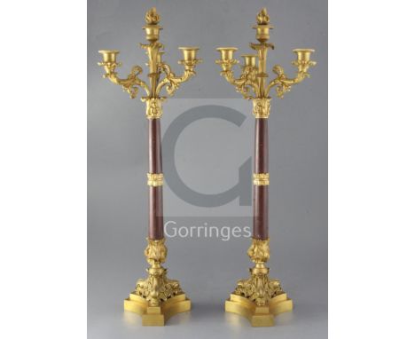 A pair of second quarter of the 19th century French ormolu and rouge marble four light candelabra, each raised on a stepped b