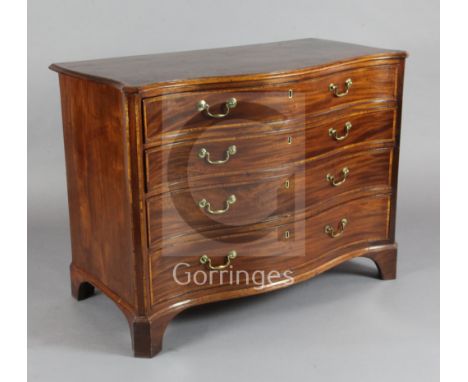 A George III satinwood banded mahogany serpentine commode, the top drawer fitted with a brushing slide, mirror, toiletry and 