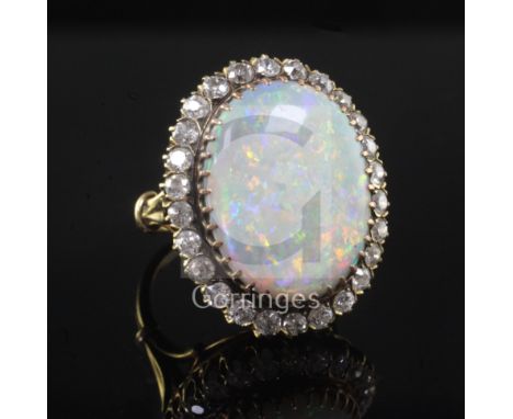 An 18ct gold, white opal and diamond oval cluster ring, the opal measuring approximately 20mm in length and bordered with old