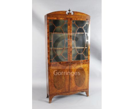 A late George III Sheraton style satinwood and burr wood bookcase, with urn finial, astragal glazed doors enclosing fixed she