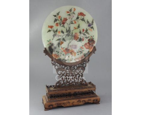 A Chinese hardstone circular plaque and hongmu stand, early 20th century, the plaque decorated with peonies and rockwork in s