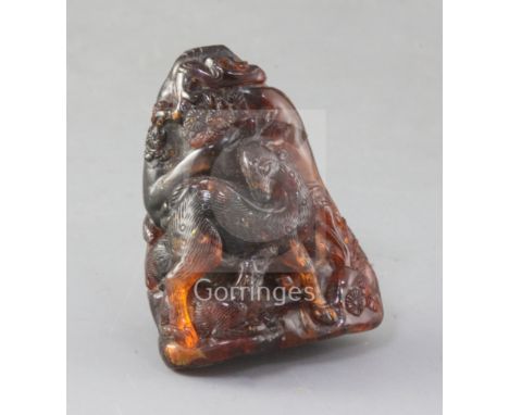A Chinese amber boulder carving, Qing dynasty, carved in high relief with two deer and a faun beside rockwork and a pine tree