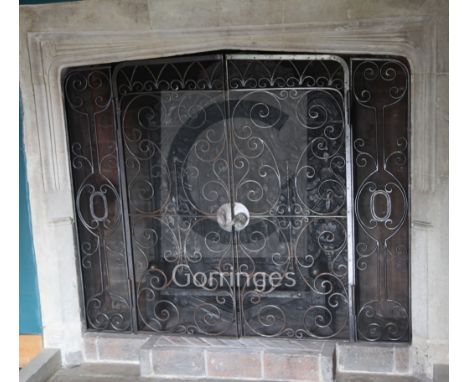 A heavy wrought iron chimneypiece spark guard, fitted a pair of doors with fork and circle design fronts, flanked by side pan