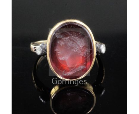 A Georgian yellow metal and oval red intaglio foil backed? ring with old cut diamond set shoulders, carved with the bust of a