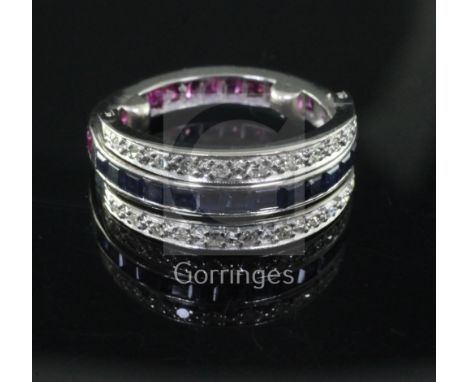 A white gold, ruby, sapphire and diamond set triple band swivel ring, set with shaped cut corundum and round cut diamonds, si