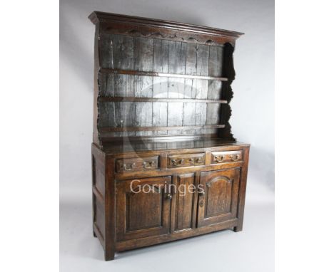 A George III oak dresser, the raised open shelf back with arched frieze and shaped sides, on fielded panel base with three dr