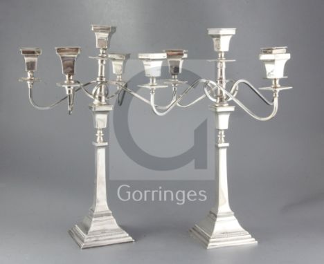 A pair of 1950's silver four branch, five light candelabra, by Alexander Smith, the detachable scrolling arms, above a taperi