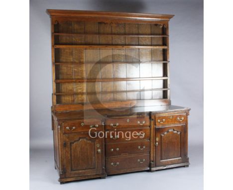 A mid 18th century oak inverse breakfront dresser, with two shelf rack, six long drawers and panelled cupboards, W.6ft 2in. D