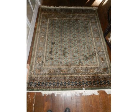 A green ground part silk Bokhara carpet with a geometric field decorated with elephant pad motifs within a multi-geometric bo