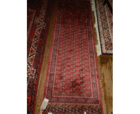 A part silk red ground Bokhara running carpet, the geometric field decorated with elephant pad motifs with multi geometric bo