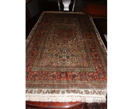 A Persian part silk ivory ground carpet, the quartered field centred with lobed foliate lozenge, multi-bordered and fringed. 