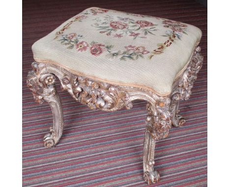 STOOL, 18th century Italian silvered wood with needlework seat on foliate carved cabriole legs, 53cm W x 47cm D. (with faults