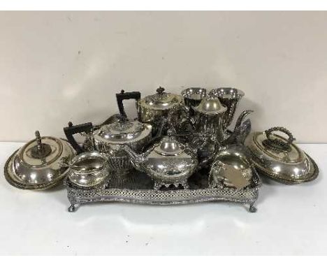 A large quantity of silver plate including twin handled gallery tray on paw feet, two four piece tea sets, two entree dishes 