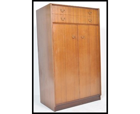 A mid century Ernest Gomme tola / teak wood bachelors wardrobe of small proportions being raised on bracket feet with twin fu