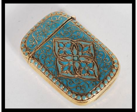 A brass and enamel vesta match case in the Anderson style having hinged lid and scrolled decoration to body.