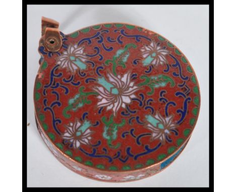 An early 20th Century Chinese enamel cloisonne magnifying glass / loop. The enamel on copper decorated with flowers on red gr