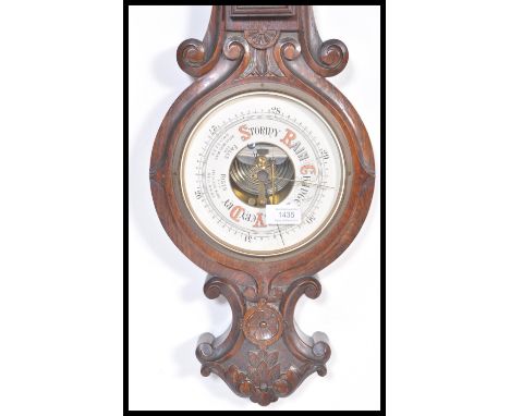 An early 20th Century oak barometer and carved scroll work. The enamel dial having painted details with silvered gauge.