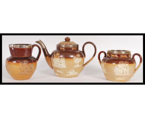 A Doulton Lambeth three piece silver mounted stoneware glazed tea service consisting of teapot, twin handled sugar bowl and c