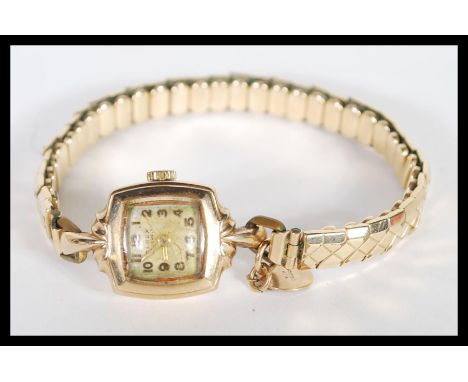 A 9ct gold ladies cocktail dress watch set to a rolled gold expanding bracelet. The watch with engine turned dial. Complete i