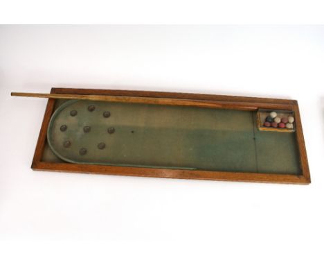 An early 20th Century oak framed bagatelle table, complete with cue and balls, 95cm long 