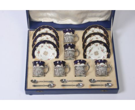 A cased set of six each Coalport floral and gilt decorated coffee cans and saucers, with pierced foliate silver mounts, hallm