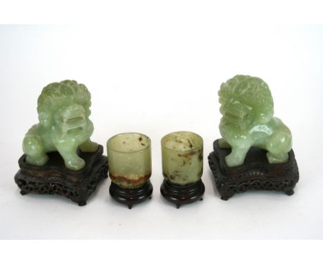 A pair of Chinese Jade small cylindrical cups, on hardwood stands, 5cm high; and a pair of Jade Dogs of Foe, 10cm high, on ha