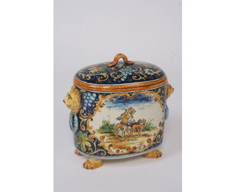 A Faience ware oval jar and cover, flanked by lion mask handles, decorated with hunting scenes, and raised on paw feet, 33cm 