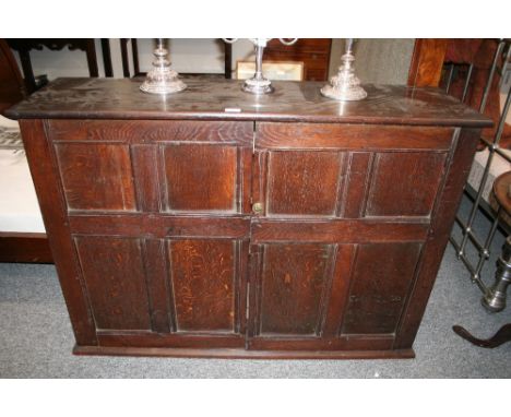 An antique oak cupboard,  the interior shelf enclosed by a pair of  quarter panelled doors, 125cm wide, 89cm high 