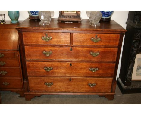 A Georgian oak and mahogany chest, of two short and three long graduated drawers, flanked by half columns and raised on brack
