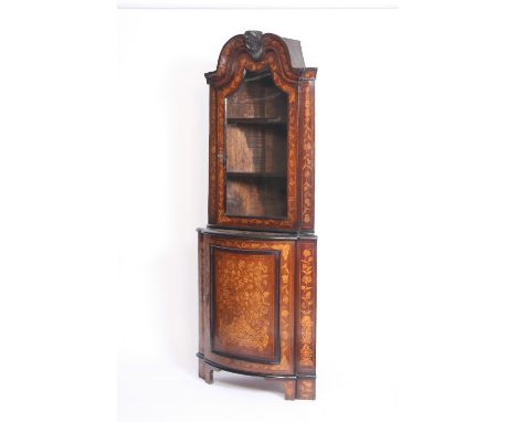 An 18th Century Dutch marquetry walnut free standing corner cupboard, the upper section surmounted by a shaped pediment and f