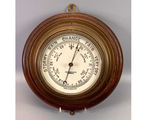 CIRCULAR BRASS CASED SHIP'S BULKHEAD BAROMETER, mounted on an oak board, John Baker &amp; Co. Ltd., Kensington, 28cms dia. 