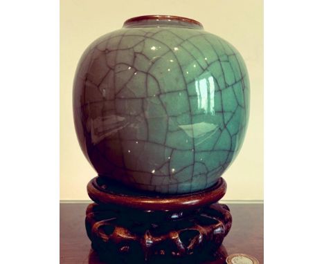 CELADON GREEN CRACKLE GLAZE OVOID VASE UPON A CARVED HARDWOOD STAND