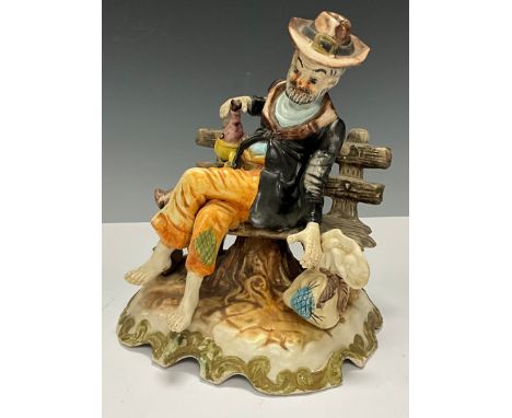A Capodimonte porcelain figure, tramp sat on a bench, he sits without shoes holding a wine bottle, 27cm high overall