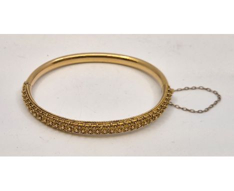 A late 19th century 15ct. gold hinged bangle, of elliptical form, with filigree work decoration to one half. (11.2g)  Conditi
