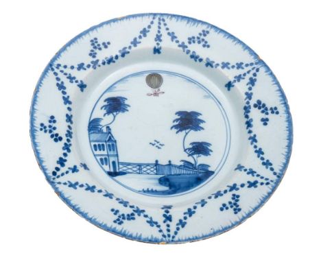 A Lambeth delftware ballooning plate: of small size, the balloon painted in green and manganese and flying over a riverside h