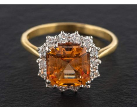 An 18ct gold, octagonal step-cut, brownish orange topaz and round, brilliant-cut diamond cluster ring,: estimated topaz weigh