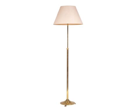 A brass adjustable standard lamp, 20th century,: the telescopic shaft above a circular base, on three lobed feet; 186cm high 