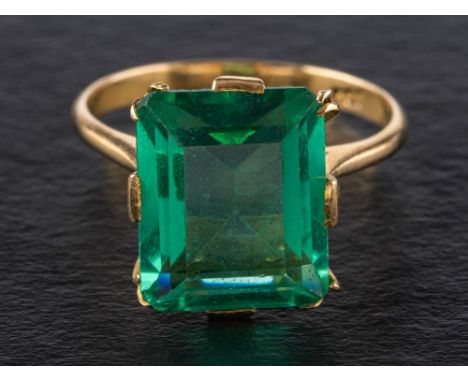 A step-cut green paste ring,: stamped '18C', length of ring head ca. 1.3cm, ring size M, total weight ca. 3.8gms. 