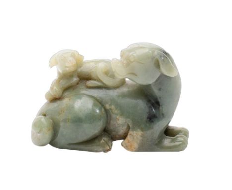 A Chinese celadon jade carving: of a reclining dog with a puppy on it's back, the stone with cream, russet and grey inclusion