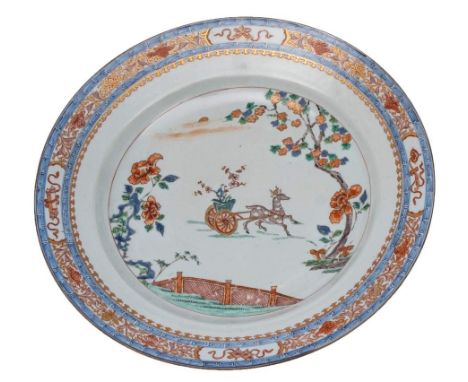 A Chinese verte/imari charger: painted with a deer pulling a cart containing a flowering plant in a vase within a fenced gard