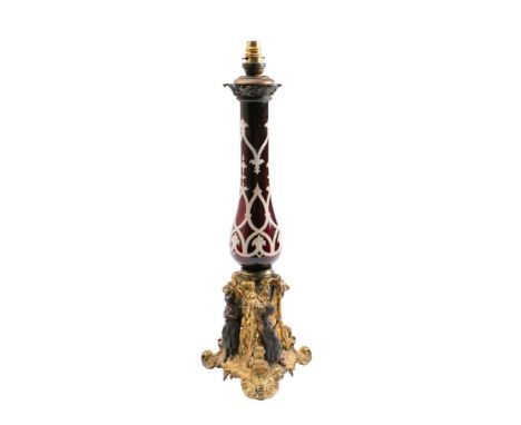 A 19th Century ruby glass and gilt brass lamp: of slender baluster form, mounted on a trefoil-shaped base with female figures