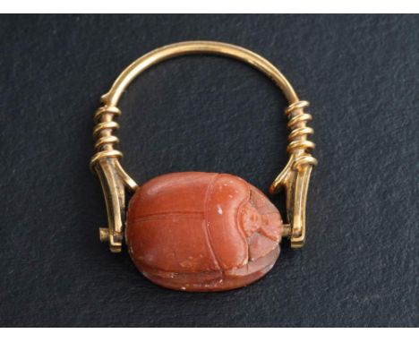 A carved carnelian scarab ring,: the ring stamped '750', length of ring head ca. 2.2cm, ring size R, total weight ca. 6.5gms.