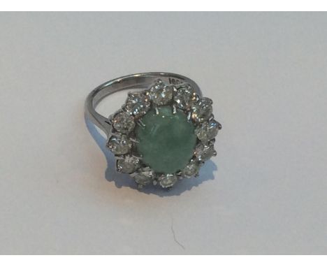 18ct white gold, jade and diamond cluster ring, centrally claw-set an oval cabochon cut jade measuring approximately 12x10mm,