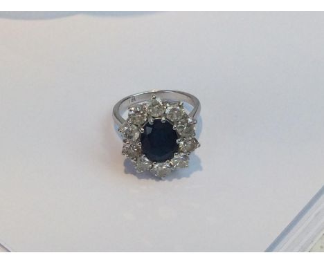 An 18ct white gold, sapphire and diamond cluster ring, 1x centrally claw-set oval faceted sapphire, approx. 10x8mm, surrounde