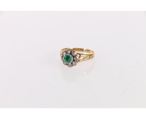 Unhallmarked yellow and white metal dress ring set with central faceted emerald green stone encircled by eight diamonds, ring