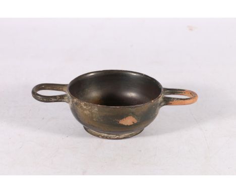 Greek black glazed skyphos of shallow form with two loop handles, impressed palmate decoration to the centre of the bowl, fla