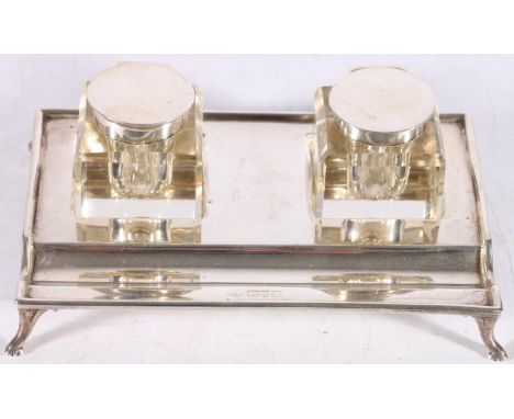 George V sterling silver desk stand of rectangular form on paw supports with two glass and silver mounted inkwells of square 