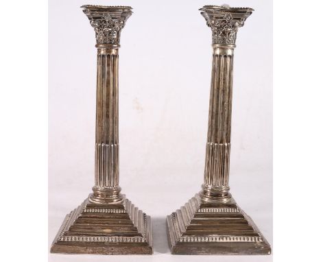 Pair of George V sterling silver Corinthian column candlesticks, each with embossed capitals on beaded square stepped loaded 